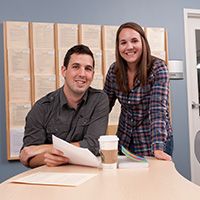 Two people reading something and smiling at the camera